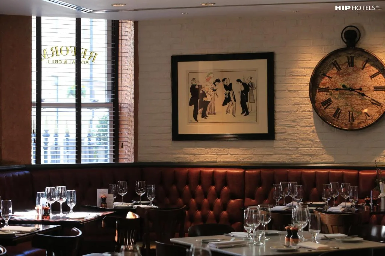 a restaurant with tables and a clock on the wall at The Mandeville Hotel in London